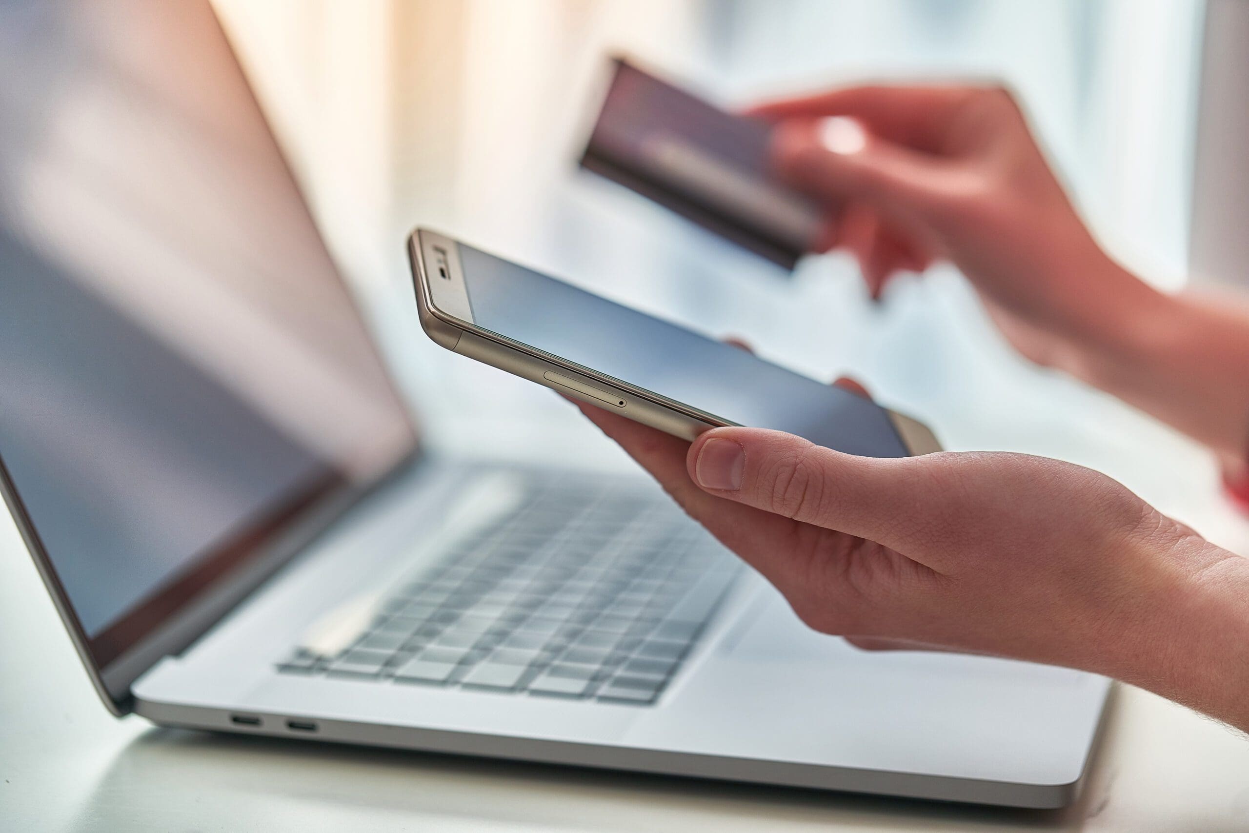 A transaction being conducted through a cell phone and a laptop.