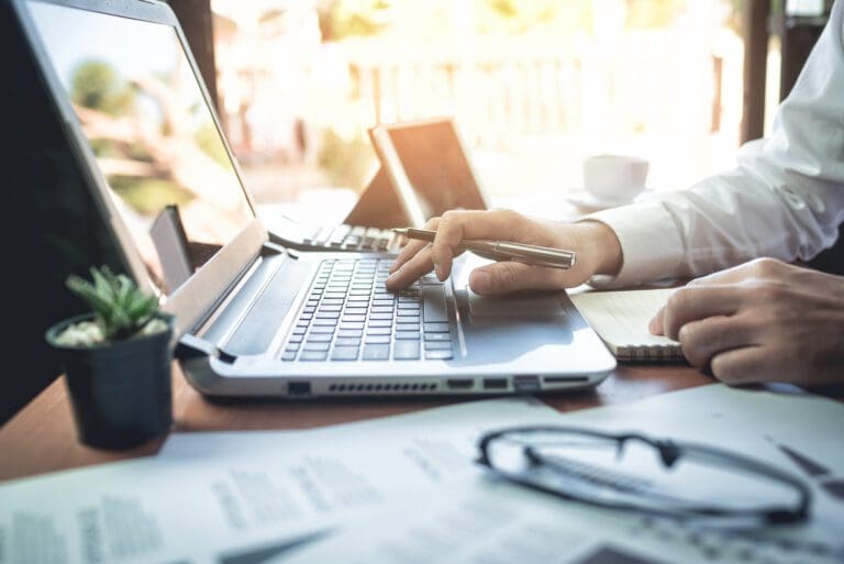 Close up of a laptop and a person working.